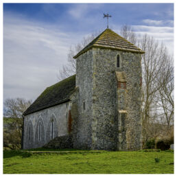 Old stone church with a pitched roof and tower set in the English countryside